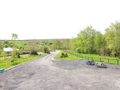 An outdoor area with a bench near a road and trees at Silver Birch Cottage in Frizington