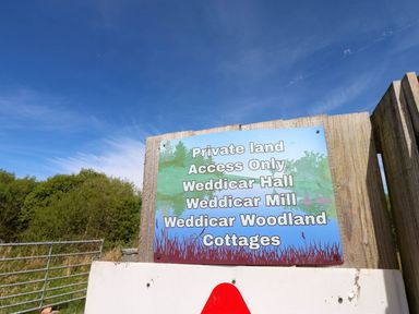 A sign indicating private land access and names of properties at Weddicar Woodland Cottages Frizington