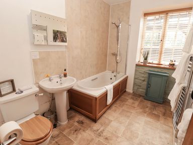A bathroom with a bath, toilet, wash basin, and window at Ty Mawr Country House in Carmarthen
