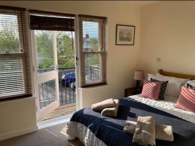 A bedroom with a bed and balcony at Admirals Rest in Weymouth