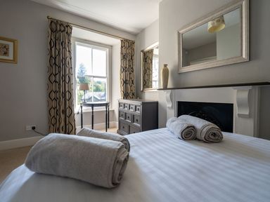 A bedroom with a bed, towels, and a chest of drawers at Gwynfryn House in Llanbedr