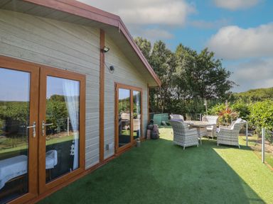 An outdoor area with a dining table and chairs at Excalabur 10 in Morfa Bychan