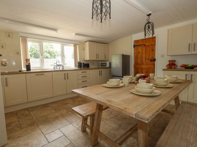 A kitchen with a table set for dining at Greenwich Cottage in Burton Bradstock