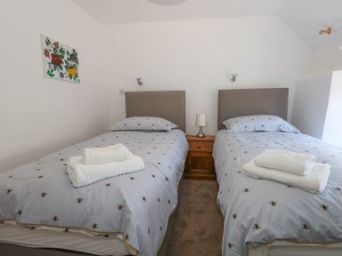 A bedroom with twin beds and a nightstand at Greenwich Cottage in Burton Bradstock
