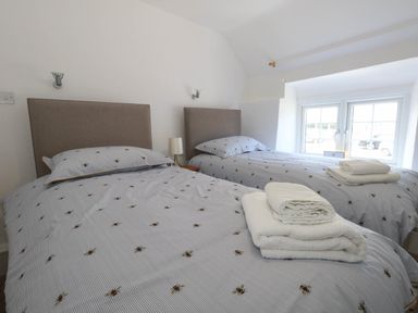 A bedroom with two beds and a window at Greenwich Cottage in Burton Bradstock