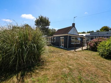 A house with surrounding grass and plants at Greenwich Cottage in Burton Bradstock