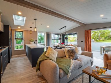 A living room with a sofa and kitchen island at Hideaway Lodge in Llanfechell