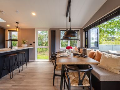 A dining room with a table set and windows at Hideaway Lodge in Llanfechell