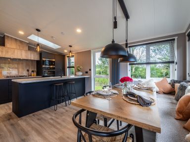 A kitchen with dining area and windows at Hideaway Lodge Llanfechell