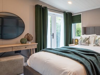 A bedroom with a bed and a console table at Hideaway Lodge Llanfechell