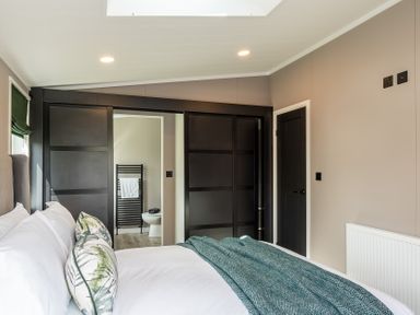 A bedroom with a bed and wardrobe at Hideaway Lodge Llanfechell