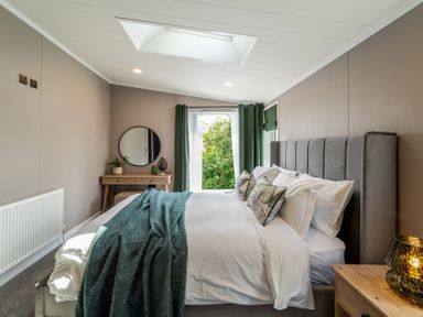 A bedroom with a bed and window at Hideaway Lodge in Llanfechell