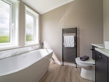 A bathroom with a bathtub and towel rack at Hideaway Lodge Llanfechell