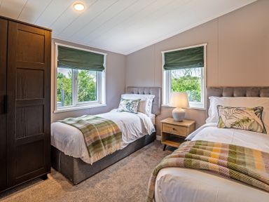 A bedroom with two beds and a wardrobe at Hideaway Lodge Llanfechell