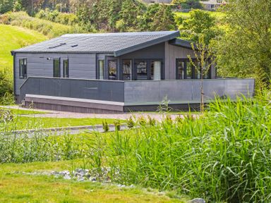 A house with a balcony surrounded by greenery at Hideaway Lodge in Llanfechell
