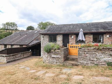 An outdoor view of a building with a stone wall and steps at Iris at Stancombe Manor Sherford near Chillington