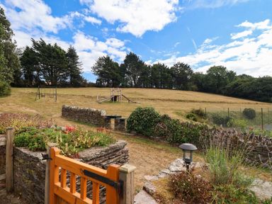 An outdoor area with a swing set and pathway at Iris at Stancombe Manor Sherford near Chillington