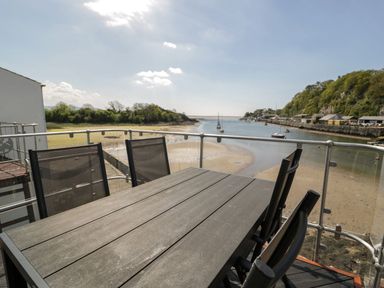 An outdoor space with a table and chairs overlooking a waterway at Seafarer's Haven in Porthmadog