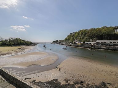 A river with boats and buildings alongside at Seafarer's Haven in Porthmadog