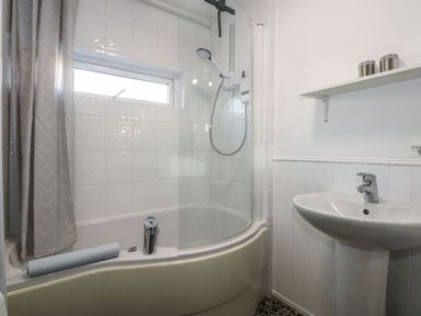 A bathroom with a shower, bathtub, and sink at Seafarer's Haven in Porthmadog