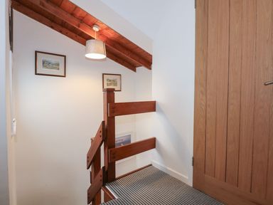 A staircase with a handrail and wall art at Seafarer's Haven in Porthmadog