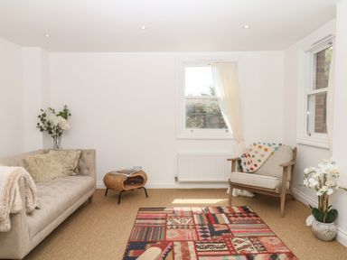 A living room with a sofa, chair, and rug at Tower View Cottage in Lympstone
