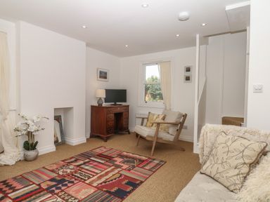 A living room with a desk and television at Tower View Cottage in Lympstone