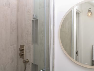 A shower with controls and a mirror at Tower View Cottage in Lympstone