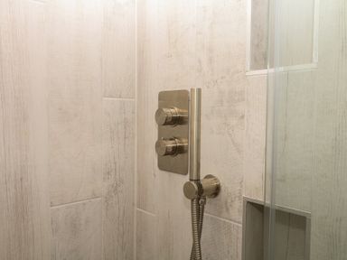 A shower with controls and a handheld showerhead at Tower View Cottage in Lympstone
