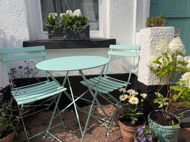 A table and chairs with flower pots in an outdoor area at Tower View Cottage Lympstone