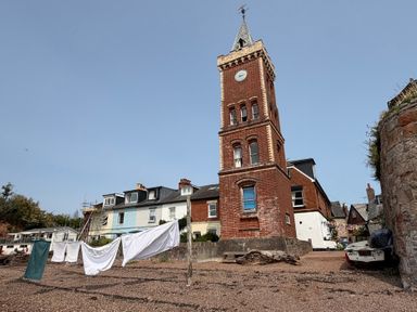 A tower and buildings with laundry on a clothesline at Tower View Cottage in Lympstone