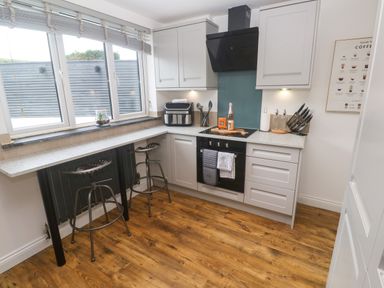 A kitchen with bar stools and modern appliances at The Lookout in Redruth