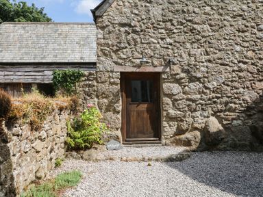 An entrance with a wooden door and stone wall at The Hayloft at Manaton