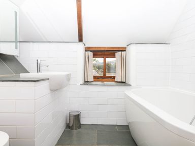 A bathroom with a bathtub and sink at The Hayloft at Manaton