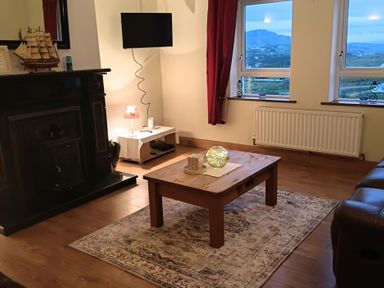 A living room with a fireplace and television at Sliabh League Mountain Lodge TEILEANN near Kilcar, County Donegal