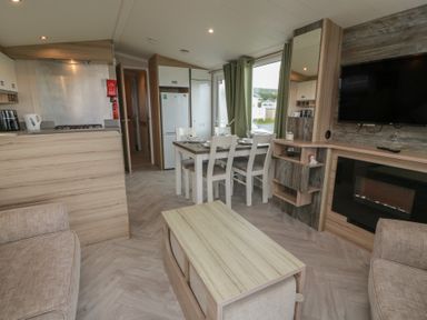 A living room with kitchen area and dining table at 101 Bay View in Ayr