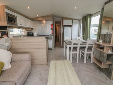 A living room with a sofa and dining area at 101 Bay View in Ayr
