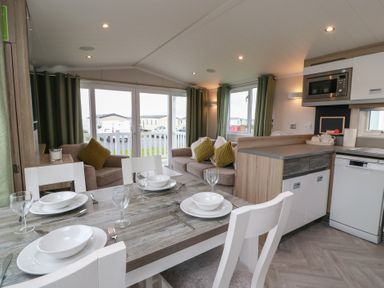 A living room with a dining table and seating area at 101 Bay View in Ayr