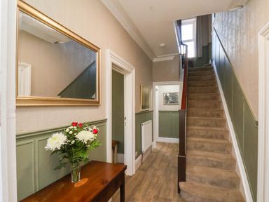 A hallway with a staircase and a mirror at Lansdowne Grange in Bridlington