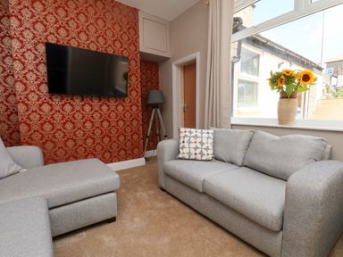A living room with a sofa and tv at Lansdowne Grange in Bridlington