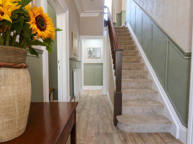 A hallway with a staircase and a vase of sunflowers at Lansdowne Grange in Bridlington
