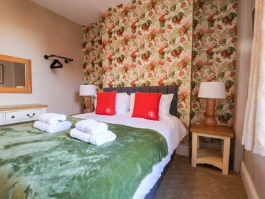 A bedroom with a bed and decorative wallpaper at Lansdowne Grange in Bridlington