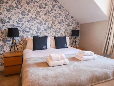 A bedroom with a bed, pillows, lamp, and towels at Lansdowne Grange in Bridlington
