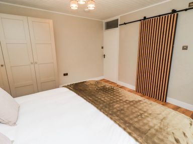 A bedroom with a bed and wardrobe at Hedley Dene Cottage in Longhorsley