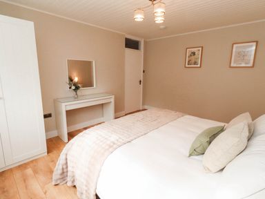 A bedroom with a bed and a dressing table at Hedley Dene Cottage Longhorsley