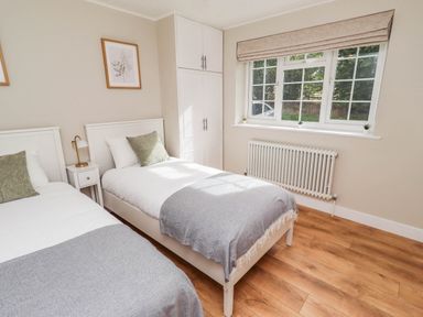 A bedroom with two beds and white furniture at Hedley Dene Cottage Longhorsley