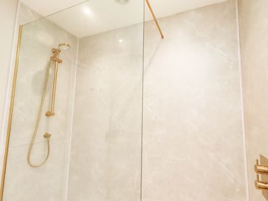 A shower with glass partition and gold fixtures at Hedley Dene Cottage Longhorsley