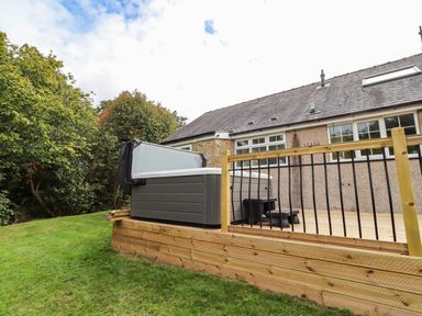 An outdoor area with a hot tub and deck at Hedley Dene Cottage in Longhorsley