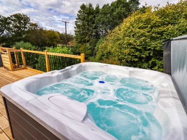 A hot tub on a wooden deck at Hedley Dene Cottage Longhorsley