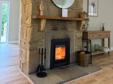 A living room with a stone fireplace and side table at Hedley Dene Cottage Longhorsley